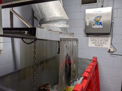 Garbage Doctor 3000 beside a chute discharge with strip curtains, over a galvanised bin