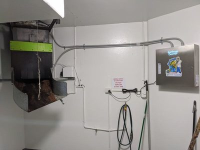 Garbage Doctor 3000 on a white wall beside a garbage chute's discharge, its conduit running to the chute