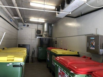 Garbage Doctor 3000 in a long rubbish room with red- and yellow-lidded bins under the chute