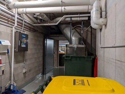 Garbage Doctor 3000 in a long, narrow bin room, a green bin under the chute