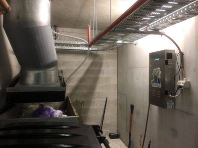 Garbage Doctor 4000 beside a large refuse chute over a bin of bagged garbage
