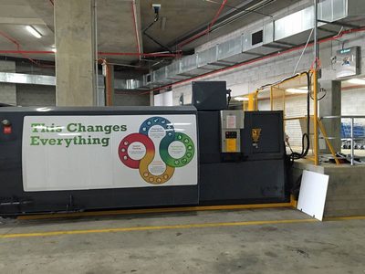 Garbage Doctor 5000 high on the wall of a loading dock, above a large waste compactor