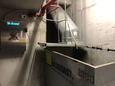 Garbage Doctor 5000 beside an angled garbage chute over a 2000-litre galvanised bin