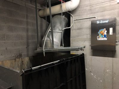 Garbage Doctor 5000 beside the chute's discharge over a large black-lidded rubbish bin