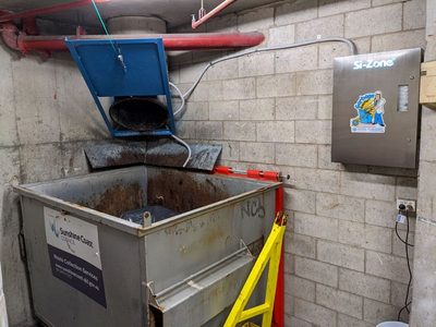 Garbage Doctor 5000 beside a garbage chute's discharge over a galvanised waste bin