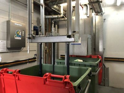 Garbage Doctor 5000 beside a chute's bin changeover, over green bins with red lids