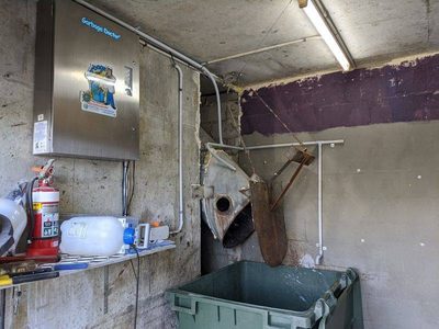 Garbage Doctor 5000 in a rubbish room, beside the chute's open door over a green bin