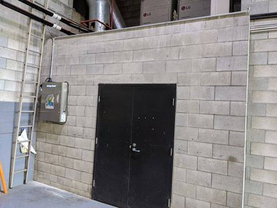 Garbage Doctor 5000 on the block wall of a waste room, beside its double doors