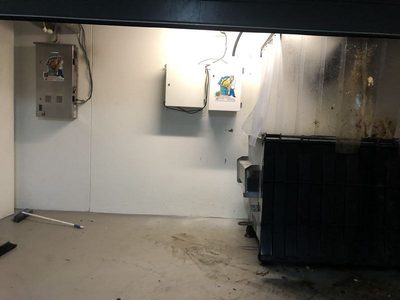 Garbage Doctor Scenting's scent tank in a rubbish room, beside a black-lidded waste bin under the chute