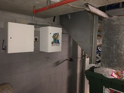 Garbage Doctor Scenting's control unit and scent tank, beside a garbage chute's discharge