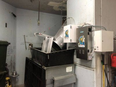 Garbage Doctor Scenting's control unit and scent tank beside a chute over a galvanised bin