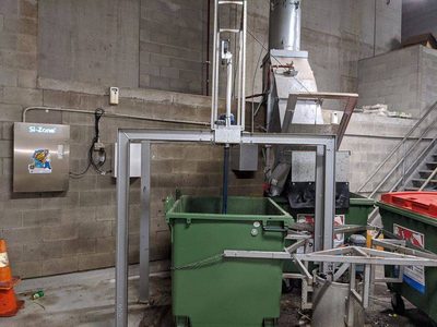 Garbage Doctor Scenting with a Si-Zone ozone unit in a garbage room with green bins under the chute