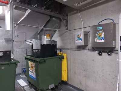 Garbage Doctor Duo and its scent tank beside a garbage chute, above a green recycling bin