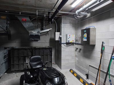 Garbage Doctor Duo beside its control panel in a basement bin room, conduit along the ceiling