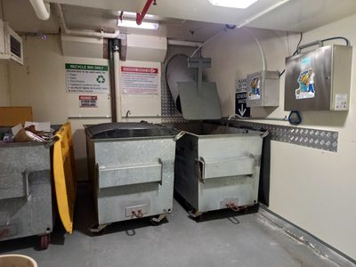 Garbage Doctor Duo beside the chute in a bin room, over galvanised recycling and general waste bins