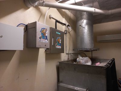 Garbage Doctor Duo beside a round refuse chute, over a galvanised bin of bagged rubbish