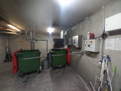 Garbage Doctor Duo in a garbage room, two green bins under the chute and its controls on the wall