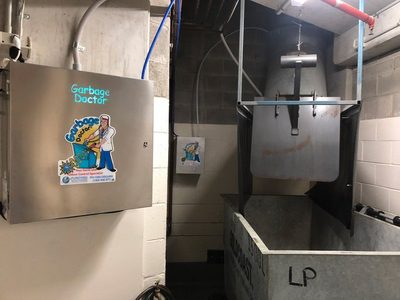 Garbage Doctor Duo beside the chute's hopper over a galvanised waste bin