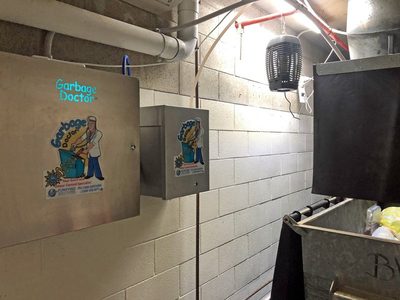 Garbage Doctor Duo and its scent tank on a block wall, beside a galvanised rubbish bin under the chute
