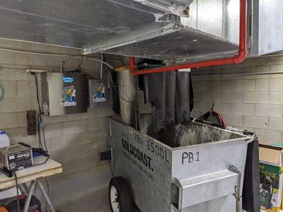 Garbage Doctor Duo beside a 1500-litre galvanised refuse bin under a garbage chute
