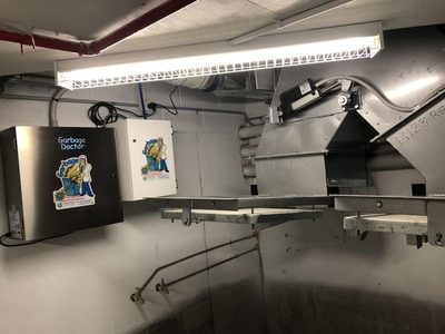 Garbage Doctor Duo and its scent tank beside the steel discharge of a garbage chute
