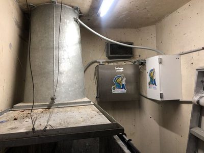 Garbage Doctor Duo and its scent tank beside a tall galvanised refuse chute