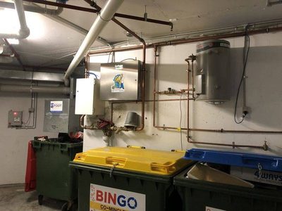 Garbage Doctor Duo and its scent tank above co-mingled recycling bins with yellow and blue lids