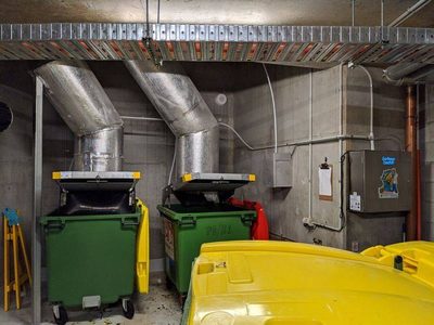 Garbage Doctor Duo beside two chute discharges, for general waste and recycling, over green bins