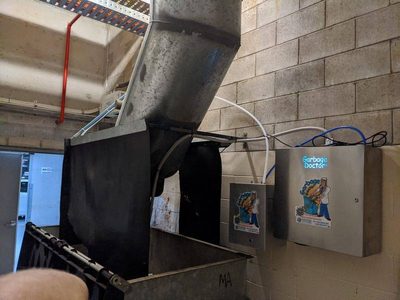 Garbage Doctor Duo and its scent tank beside an angled refuse chute over a galvanised bin
