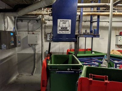Garbage Doctor Duo beside an Elephants Foot waste compactor, with green and red bins