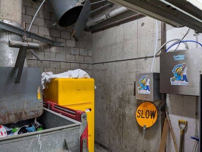 Garbage Doctor Duo and its scent tank above a galvanised rubbish bin, beside the chute's hopper
