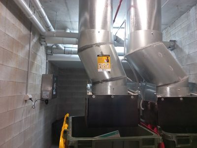 Garbage Doctor Ozone beside two angled refuse chutes over their bins