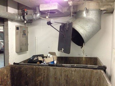 Garbage Doctor Platinum on the wall of a rubbish room, beside an angled chute over a large refuse bin