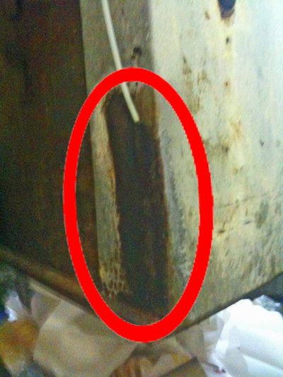 A galvanised chute discharge corroded where a spark-type generator's thin white tube enters, ringed in red