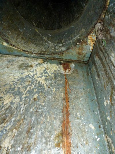 Rust running the full height of a rubbish chute's discharge, from a corona discharge generator's entry point