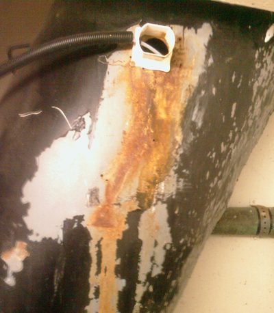 Paint stripped and rust running down a black steel refuse chute, below a corona discharge generator's hose fitting