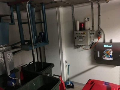 A Garbage Doctor 3000 beside a switchboard, above the bins
