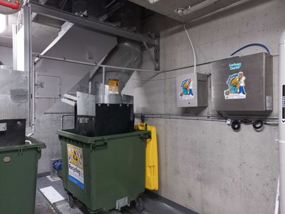 A Garbage Doctor Duo and its scent tank beside a garbage chute, above a green recycling bin