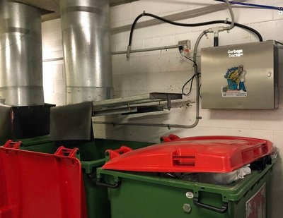 A Garbage Doctor Ozone on the wall above red- and green-lidded bins
