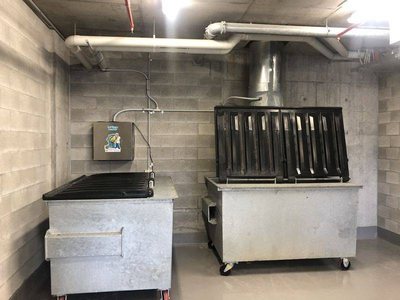 A Garbage Doctor Ozone beside a garbage chute, over two large bins
